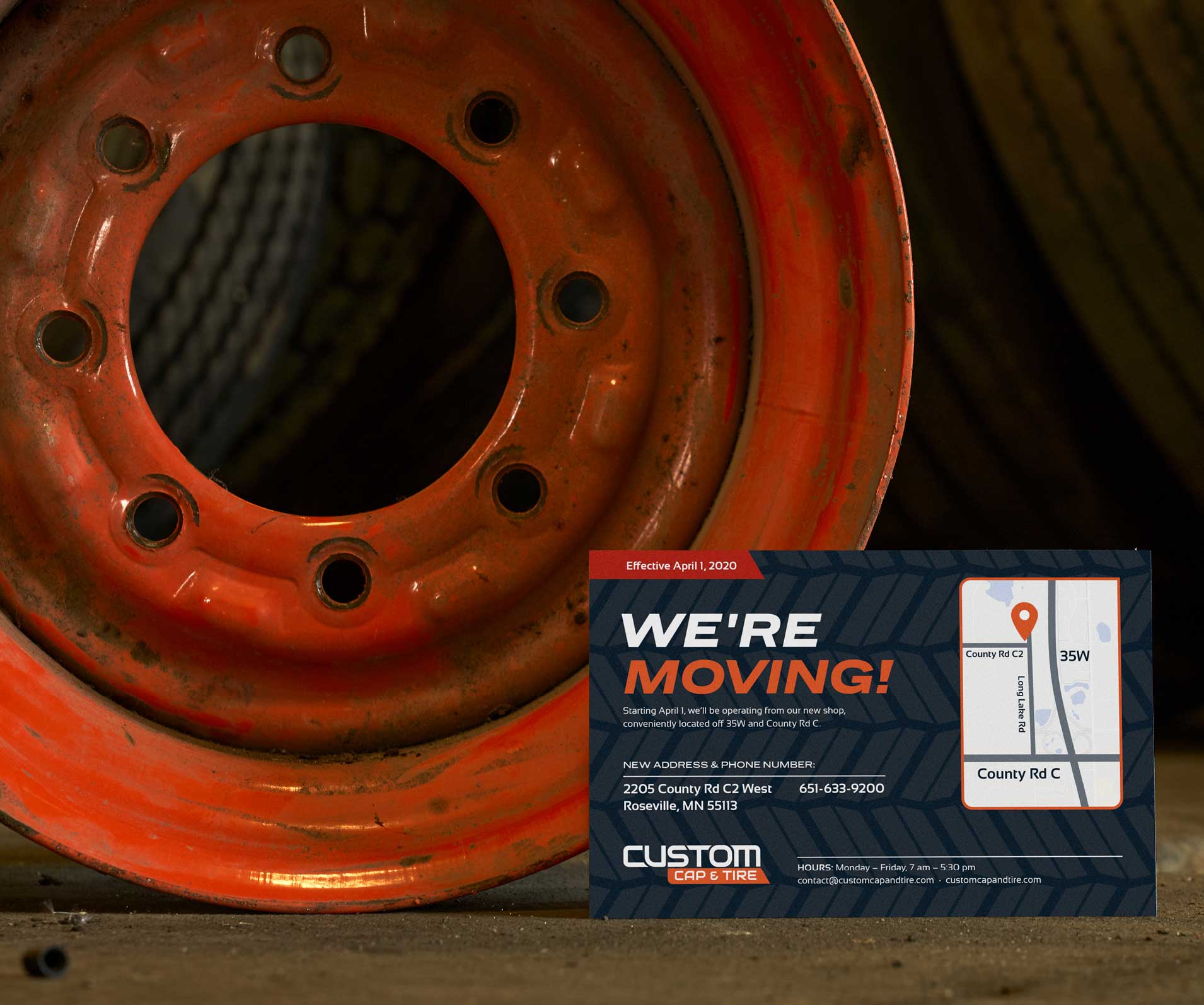 A We're Moving postcard in front of an orange tire wheel well.