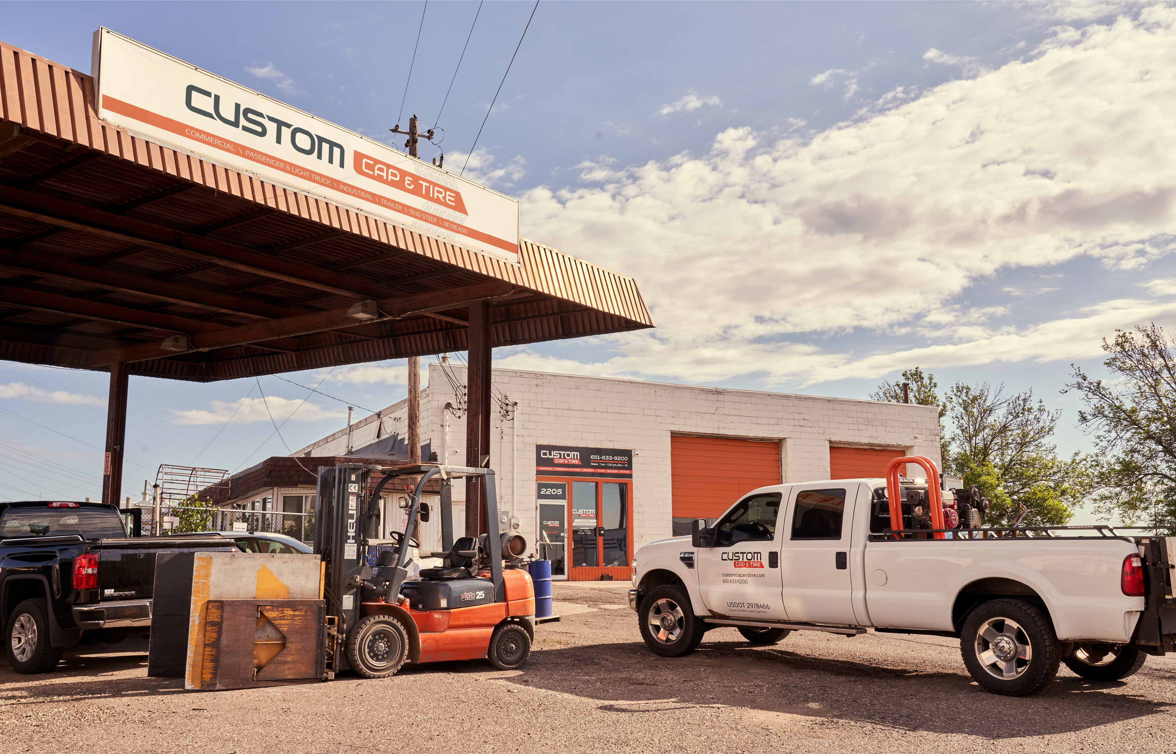 Custom Cap and Tire awning signage and truck decals, with the main building in the background.