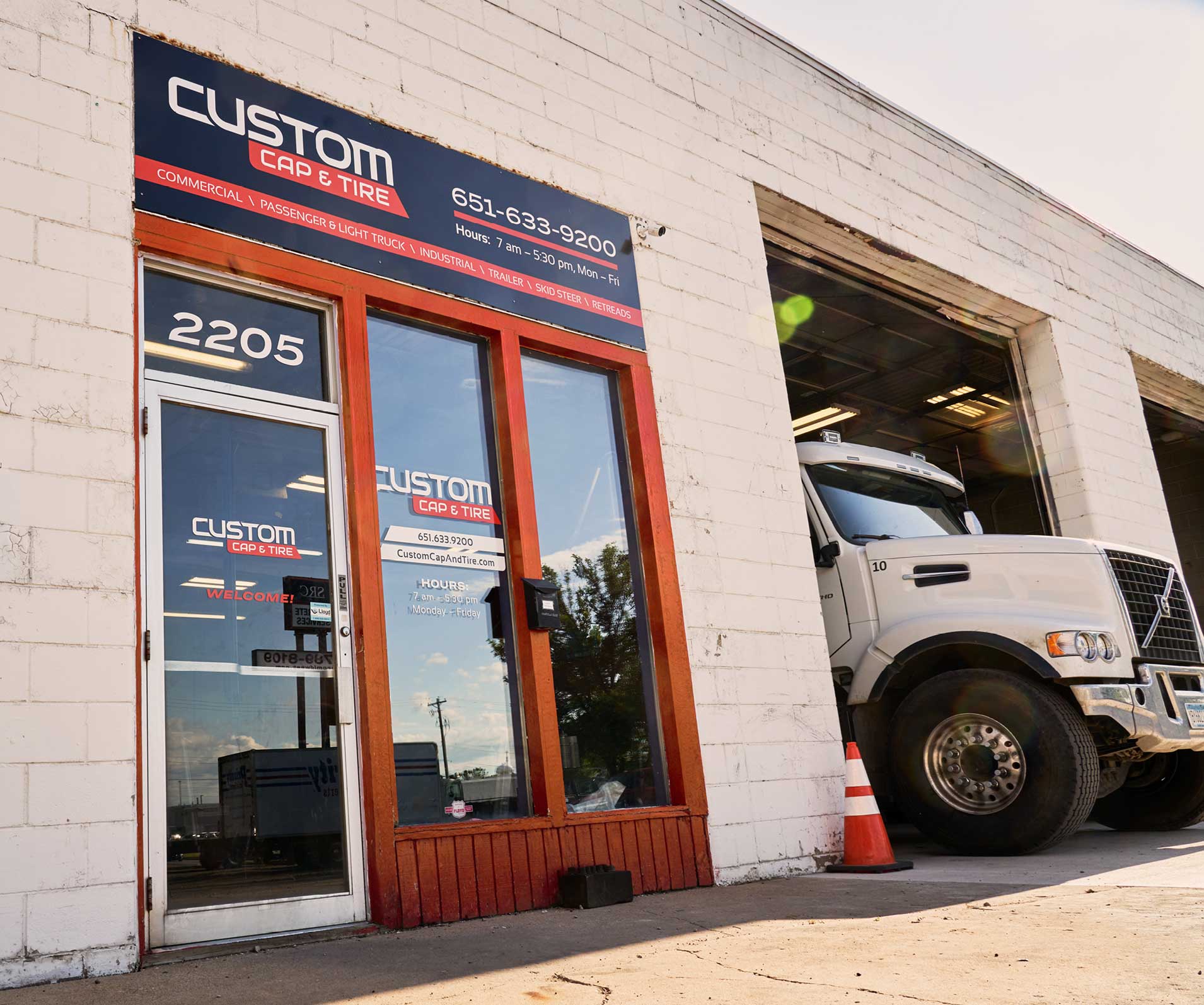 The entryway to Custom Cap and Tire's building features overhead signage and window graphics.